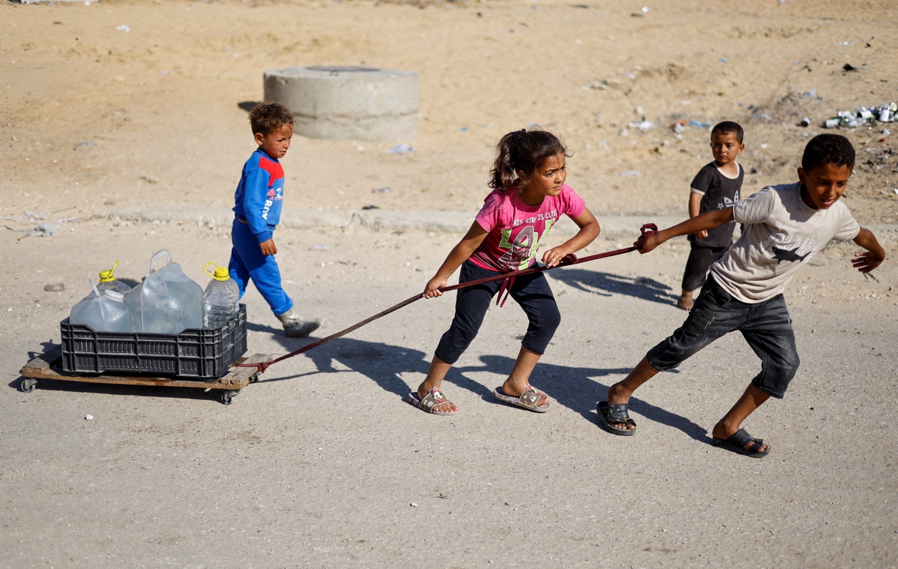 PHOTO: Palestinian children pull water containers as people flee Rafah after Israeli forces launched a ground and air operation in the eastern part of the southern Gaza city in the southern Gaza Strip, May 9, 2024. 